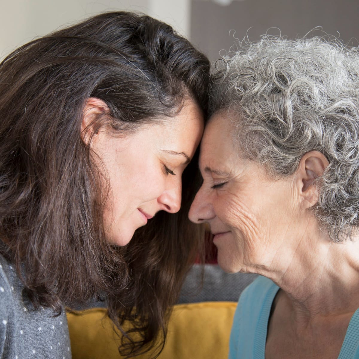 Older woman and her daughter touching foreheads with their eyes closed