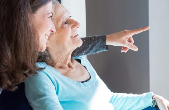 Older woman and her daughter sitting down and looking out a window